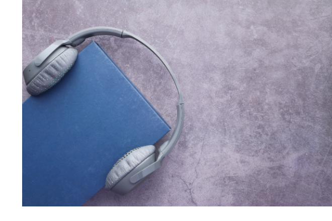 Un livre avec une couverture bleue porte une paire d’écouteurs gris.