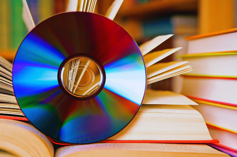 Un CD est posé contre un livre ouvert à côté d’une pile de livres supplémentaires.