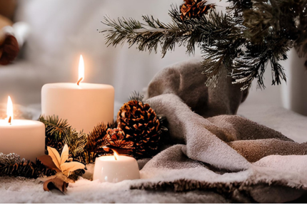 Deux bougies allumées en blanc sont entourées de branches de pin, de pommes de pin et d'une couverture blanche.