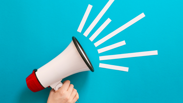 A hand holds up a megaphone on a blue background.