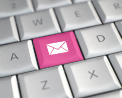 A close up of a computer keyboard shows a pink button with the image of an envelope.
