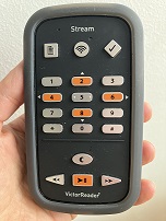 Gros plan d'une main tenant un lecteur Victor Stream avec l'avant de l'appareil visible.