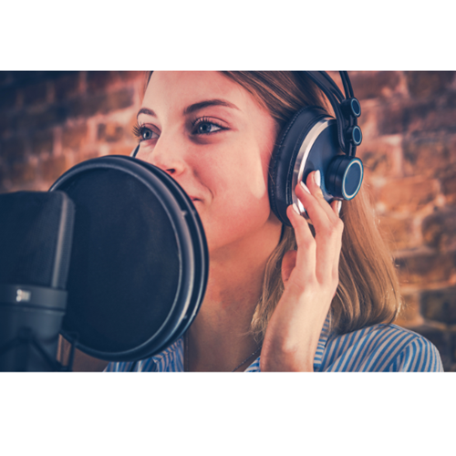 a woman wearing headphones speaks into a large microphone