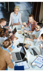 Un groupe de collègues discute autour d'une table couverte d'ordinateurs portables.