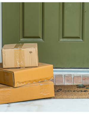 A stack of cardboard boxes sit in front of a green door.