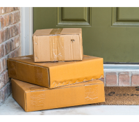 A stack of packages sits outside a residential front door.