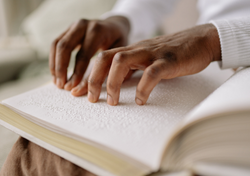 Two hands read a braille book.