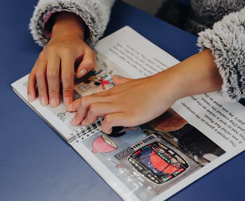Hands on a printbraille book.