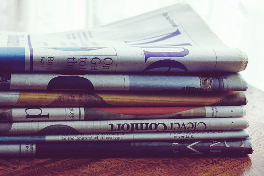 A stack of folded newspapers on a table.
