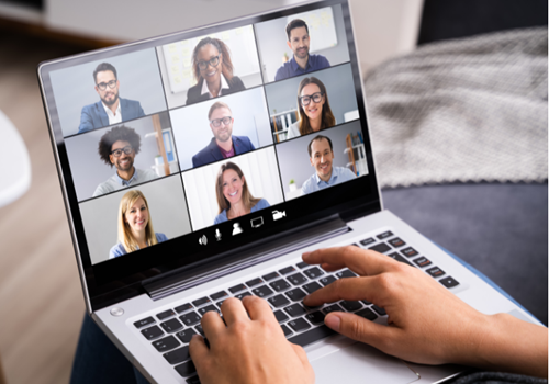 A laptop screen shows a series of faces. Hands type on the keyboard of the laptop.