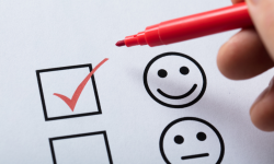 A red marker hovers above a box with a red checkmark. Beside the box is a happy face graphic. Below the happy face graphic is another box and a neutral face graphic.