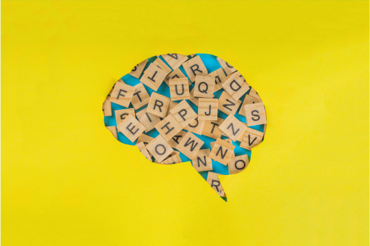 une bulle de dialogue en forme de cerveau comporte des tuiles avec diverses lettres dispersées sur la bulle.