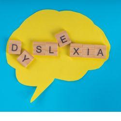 a brain shaped dialogue bubble has the word dyslexia scattered over the bubble
