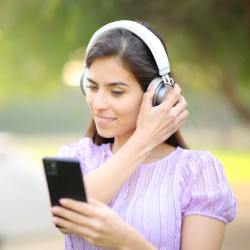Une femme porte des écouteurs et tient son téléphone.