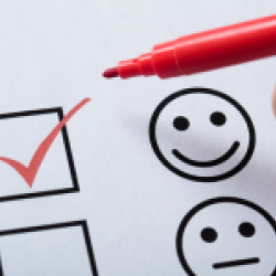 A red marker hovers above a box with a red checkmark. Beside the box is a happy face graphic. Below the happy face graphic is another box and a neutral face graphic.