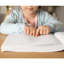  Un jeune enfant lit un livre en braille à une table.