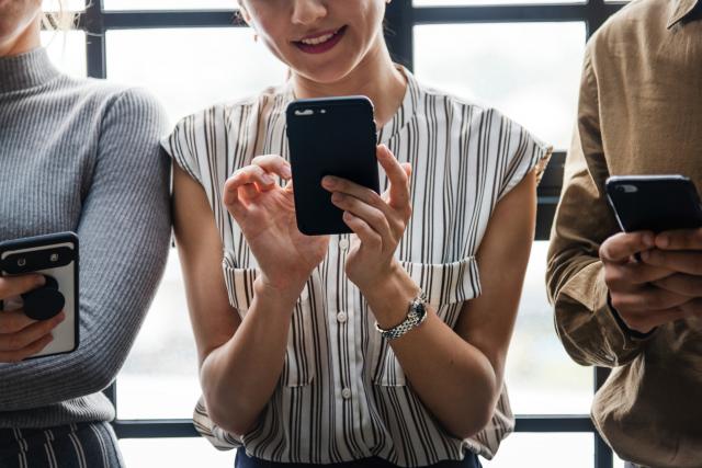 Une femme dans un chemisier rayé tenant un appareil mobile