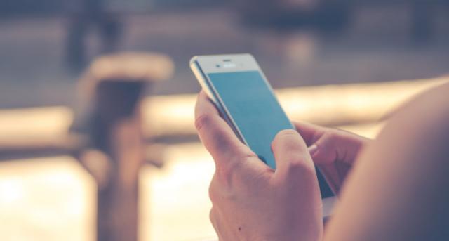 Gros plan des mains d’une femme tenant un iPhone à l’écran bleu