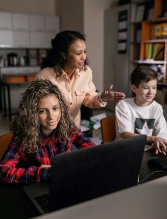 Teacher standing behind two students using laptops